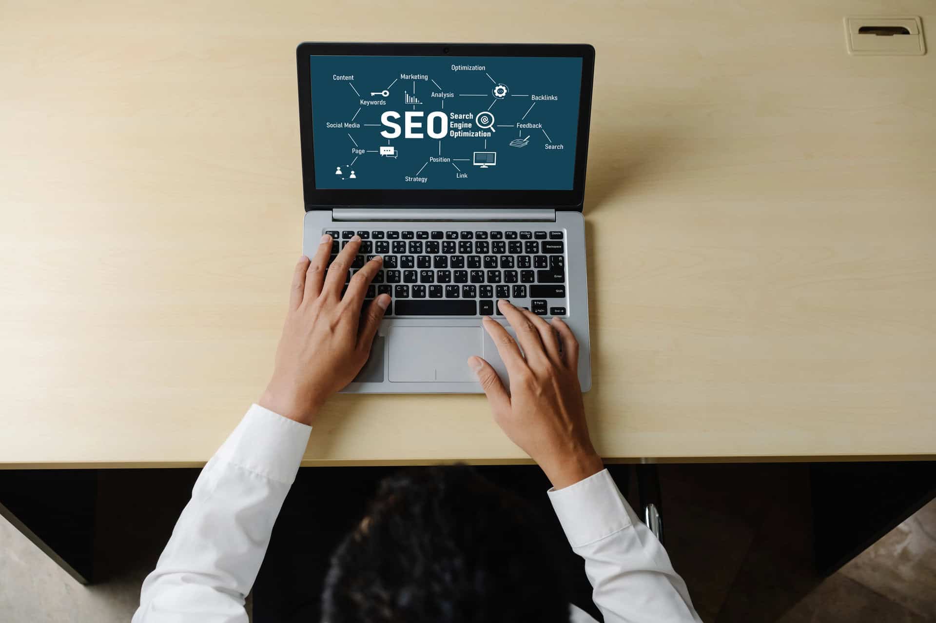 Hands typing on a laptop displaying SEO strategy and keywords, illustrating Delaware Digital Media's SEO